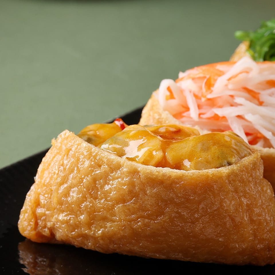 Close-up of Bloop Bloop's inari sushi, one filled with a golden topping, another with shredded crab.