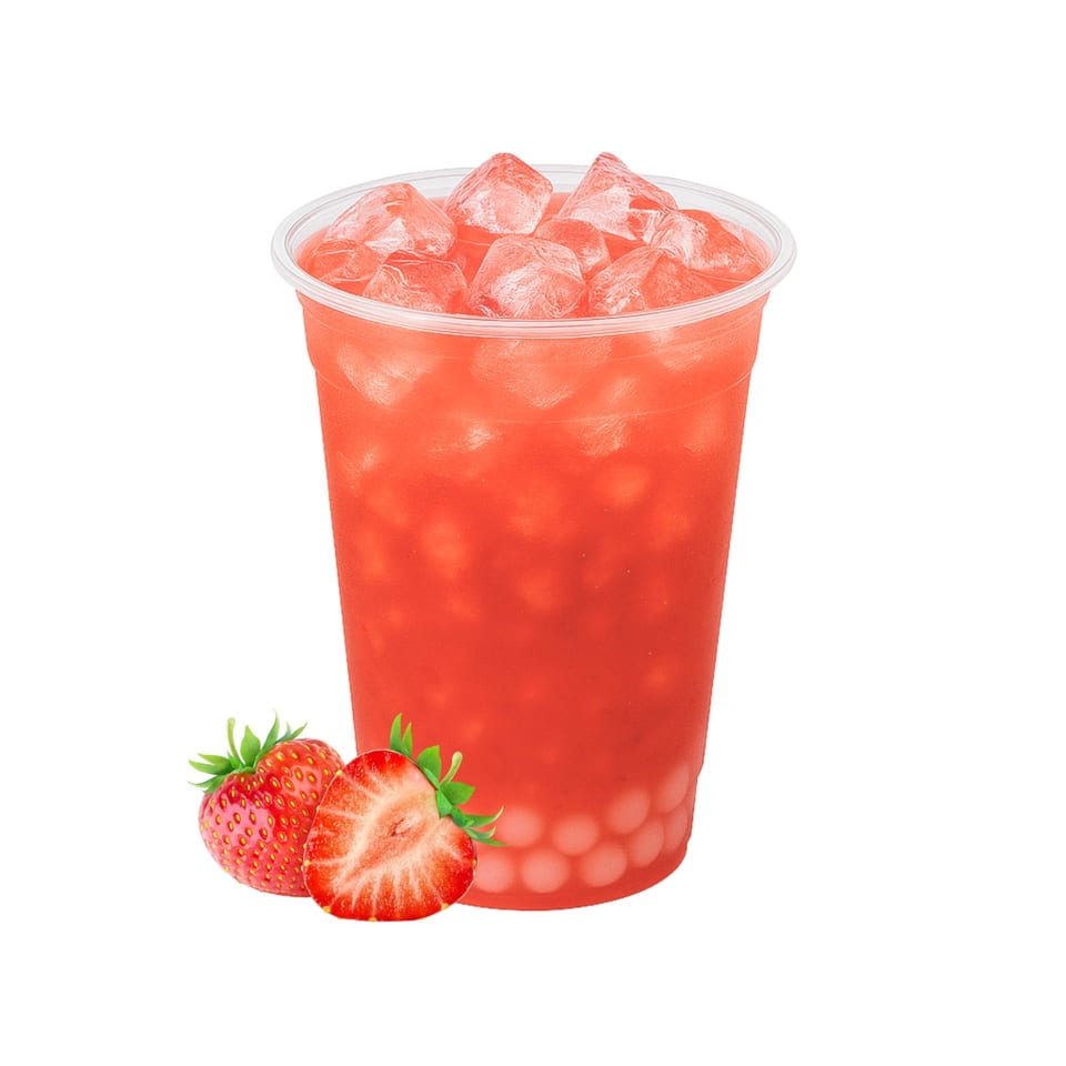 Strawberry boba tea with ice in a clear plastic cup, with two fresh strawberries beside it.