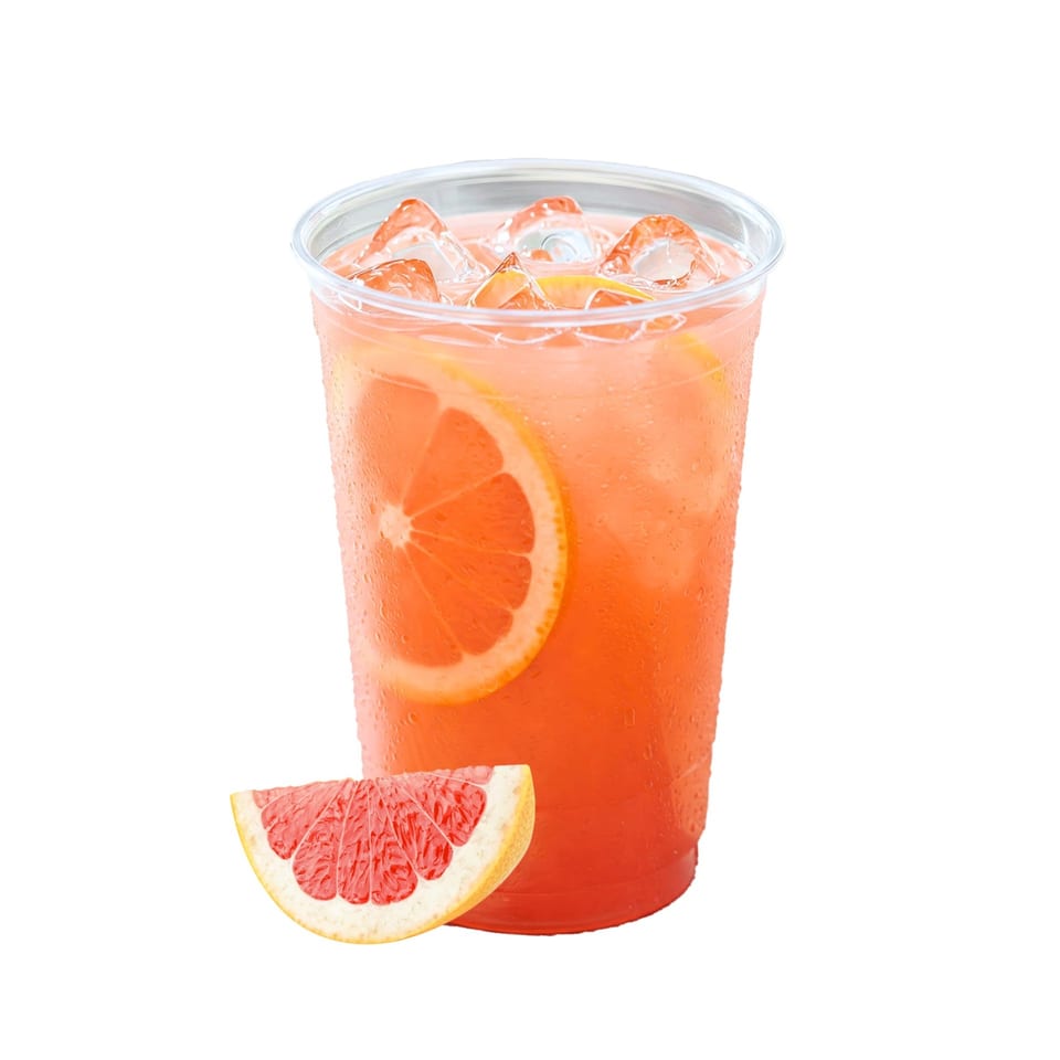 Iced grapefruit drink in a plastic cup with a grapefruit slice on the side.